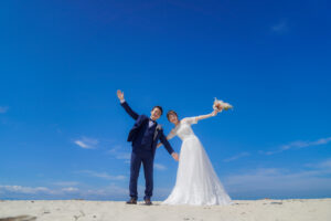内海海岸で前撮りロケーションフォトウェディング　ビーチて手を広げて立つ花嫁と花婿