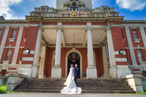 市政資料館でウェディングドレス前撮り　外観と青空と背中合わせの新郎新婦