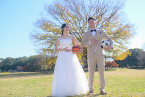 紅葉の庄内緑地公園で秋の前撮りロケーション　バスケットボールとサッカーボールを持つ新郎新婦