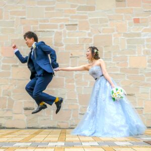 久屋大通庭園フラリエで洋装フォトウェディング　おしゃれな壁の前で新郎がジャンプ　前撮りポーズアイデア
