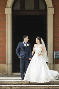 市政資料館で洋装ウェディングフォト　手を繋いで見つめ合う新郎新婦　愛知の前撮りスポット