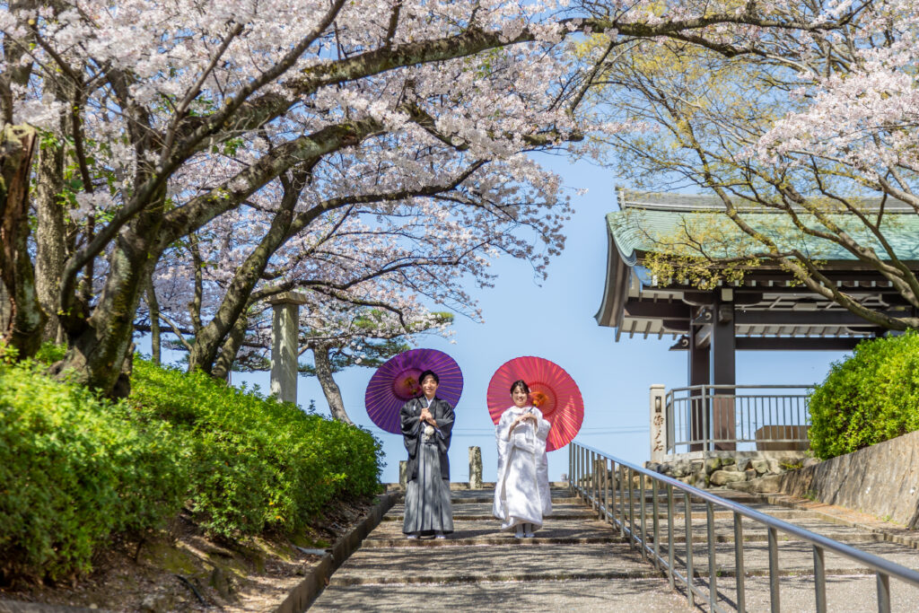 覚王山日泰寺にある階段で和傘をさして微笑む和装姿の新郎新婦