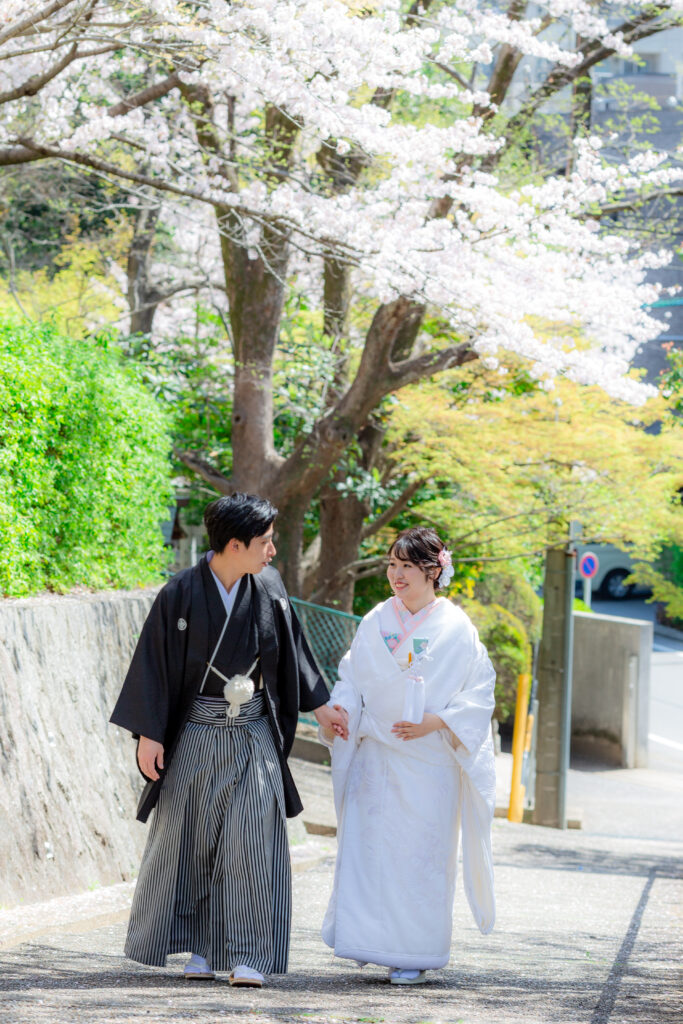 揚輝荘の外にある道路を歩く白無垢姿の新婦と新婦をエスコートする紋付き袴姿の新郎