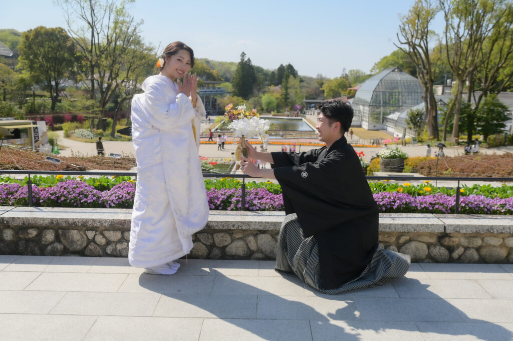 東山植物園内でプロポーズ風のポーズを撮る和装姿の新郎新婦