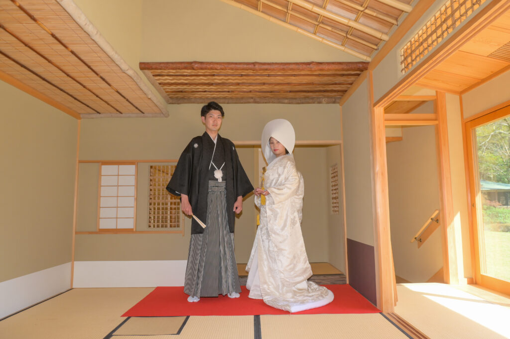 東山植物園内の宗節庵でポーズを決める紋付き袴姿の新郎と綿帽子を被った白無垢姿の新婦