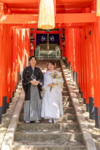 揚輝荘で和装ウェディングフォト　赤い鳥居の下で笑顔の新郎新婦　白無垢前撮り