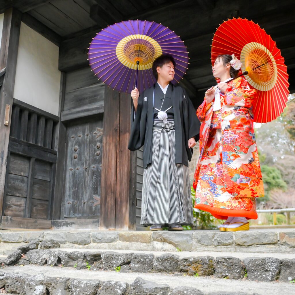 東山植物園内で和傘をさす紋付き袴姿の新郎と色打掛姿の新婦