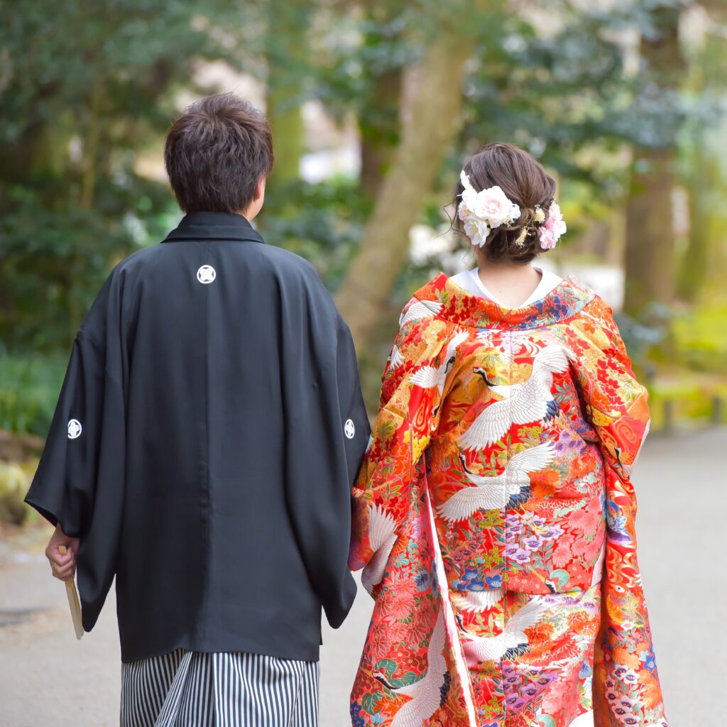 東山植物園内を歩く紋付き袴姿の新郎と色打掛姿の新婦の後ろ姿