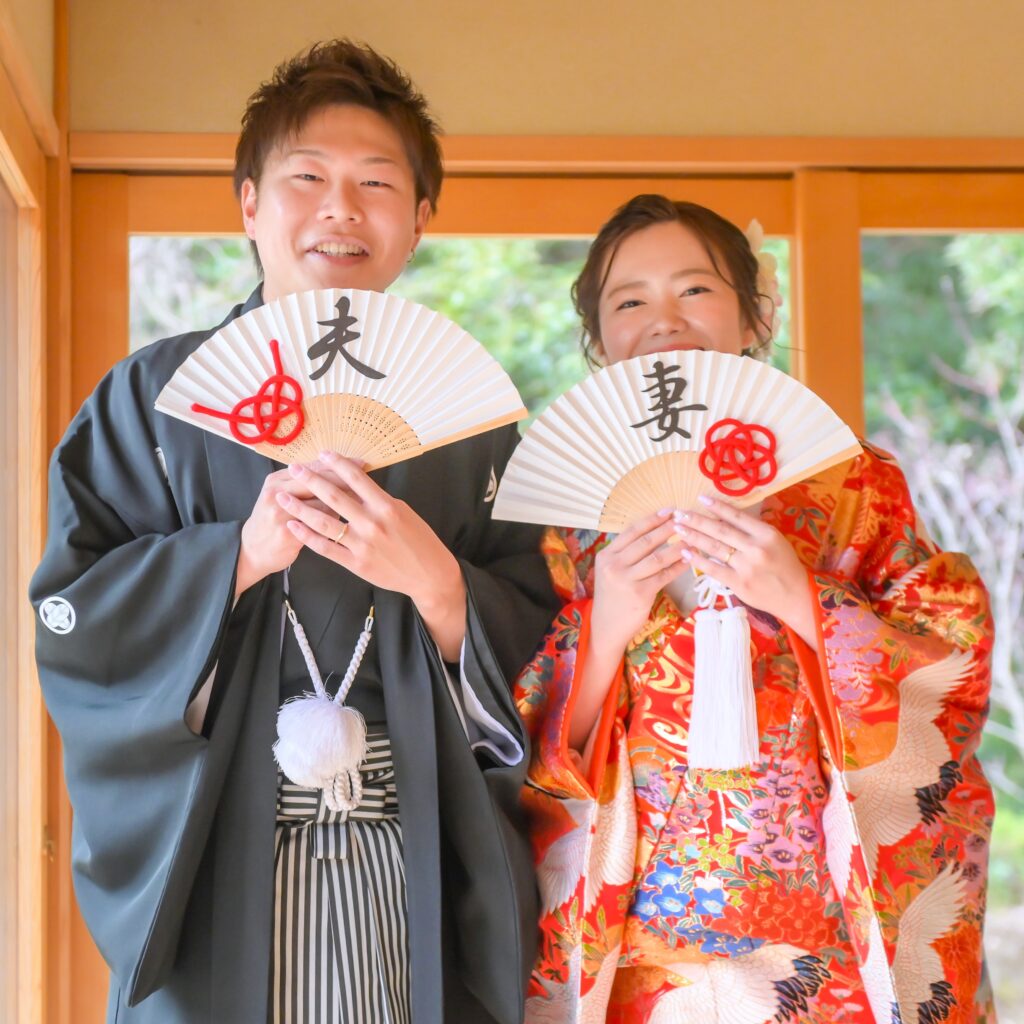 東山植物園内の宗節庵で夫婦と書かれた扇子プロップスをもって笑顔の新郎新婦