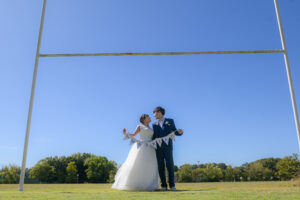 青空の下ガーランドを持つ新郎新婦